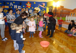 Dzieci i rodzice wrzucają monety do miski z wodą.